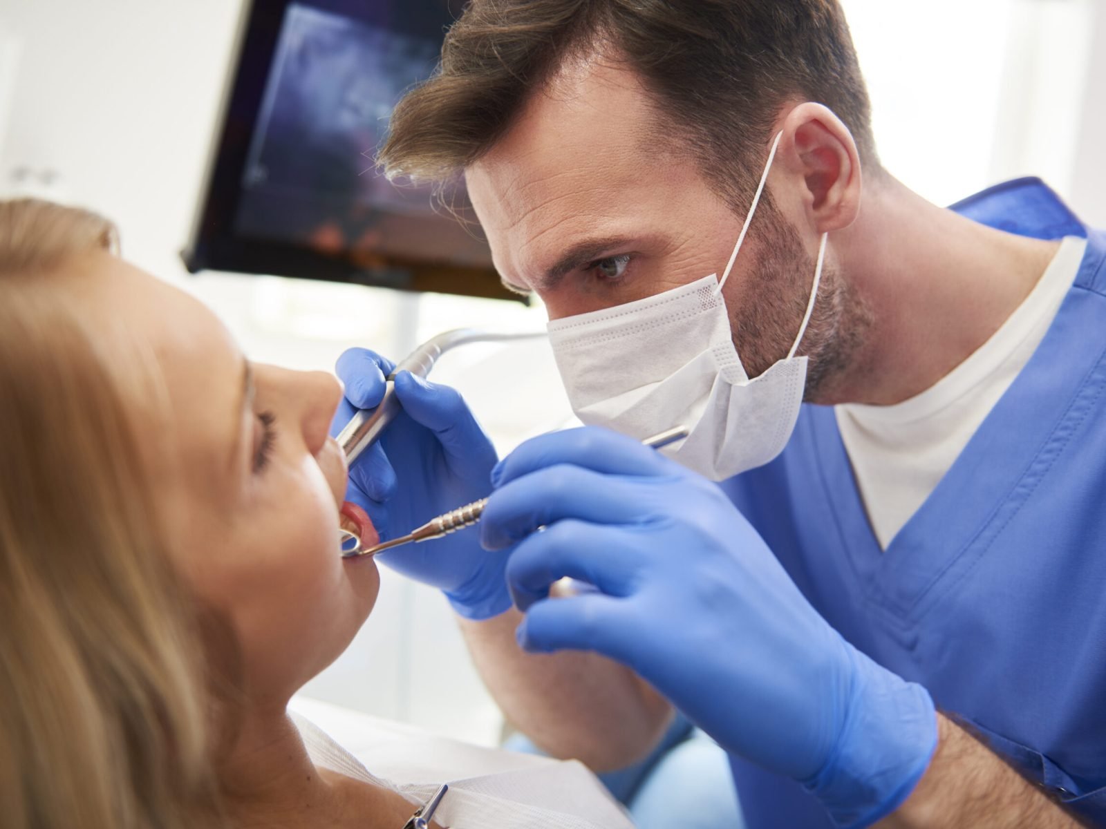 Focused stomatologist treating woman for dental cavity